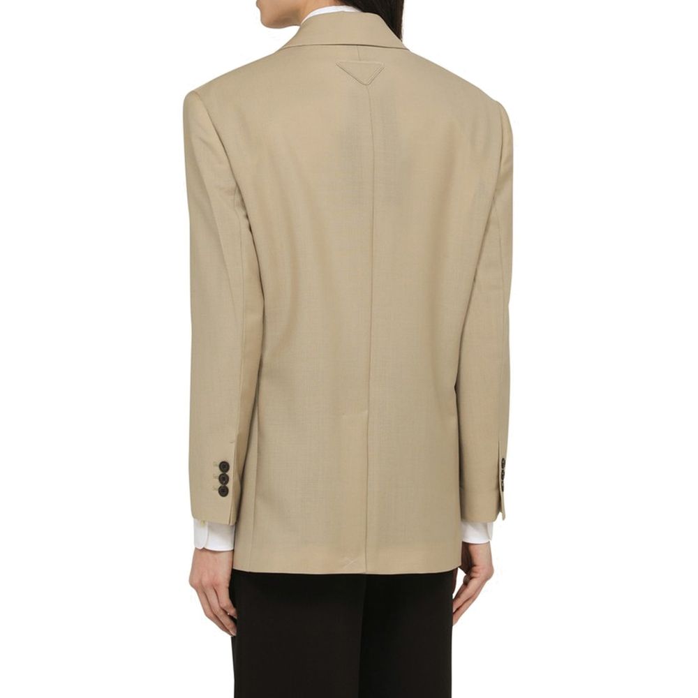 Elevate your wardrobe with the Prada Beige Mohair Blazer, a luxurious blend of mohair and virgin wool, embodying timeless elegance and sophisticated craftsmanship.