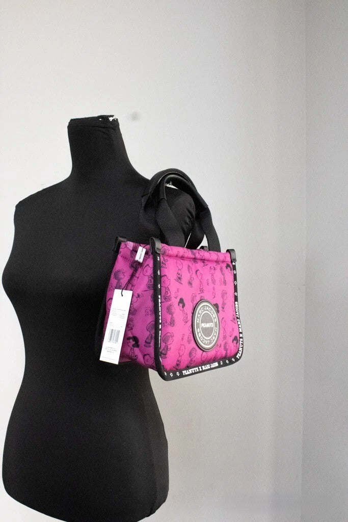 Discover the Marc Jacobs X Peanuts Mini Fuchsia Fedora Tote, a limited edition masterpiece in durable nylon, blending whimsical charm with exquisite craftsmanship for the discerning fashion connoisseur.