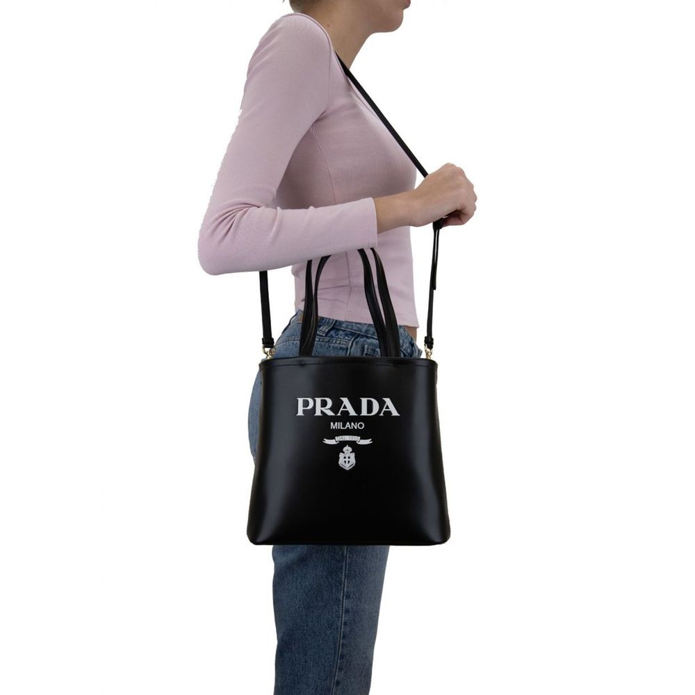 Indulge in the Prada Black Calfskin Tote Bag, a masterpiece of artisanal luxury crafted from 100% calf leather, perfect for the discerning individual who values elegance and sophistication.