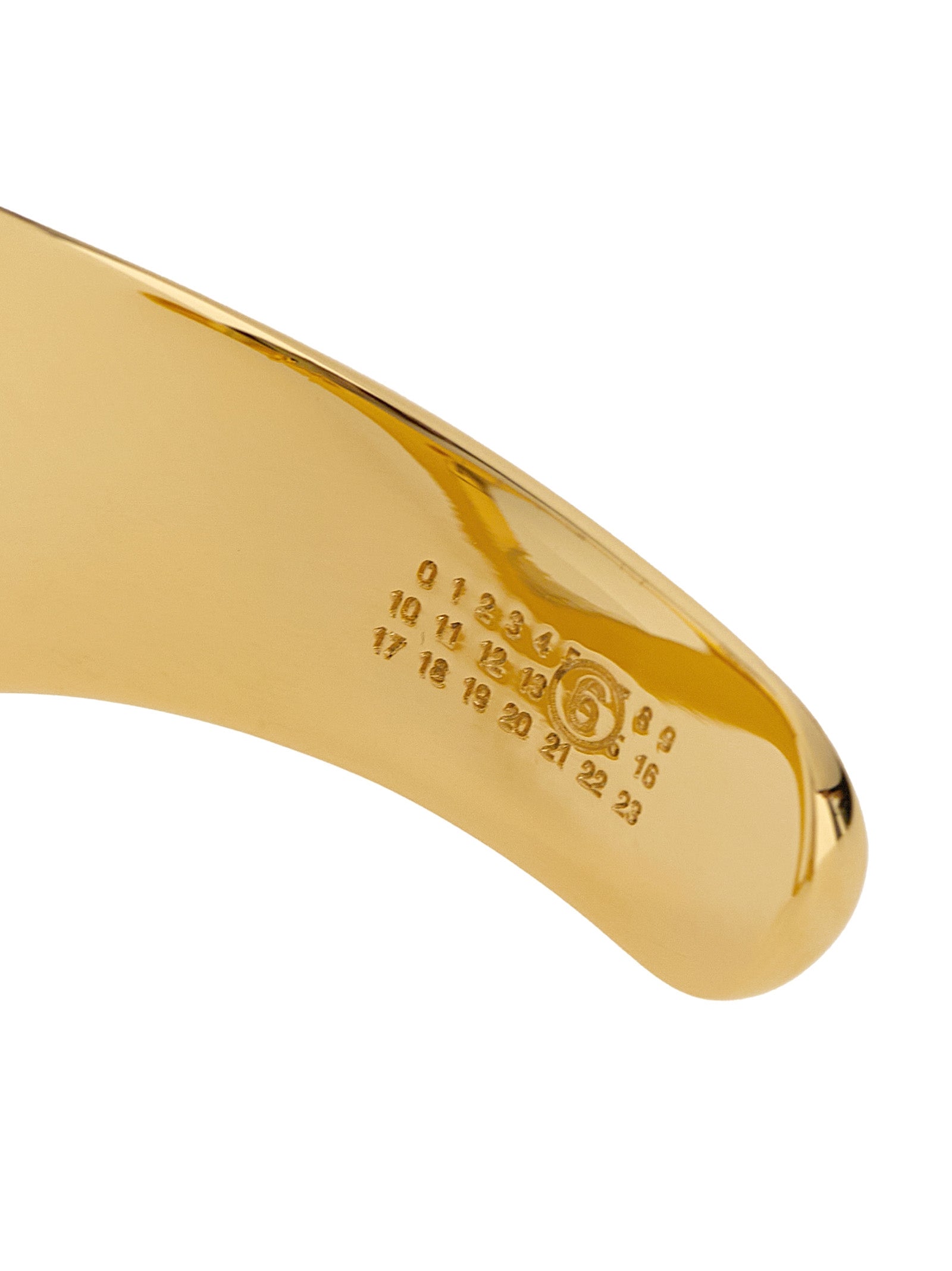 Elevate your elegance with the MM6 Maison Margiela Gold Brass Bracelet, a masterpiece of gilded craftsmanship that embodies timeless sophistication and refined allure.