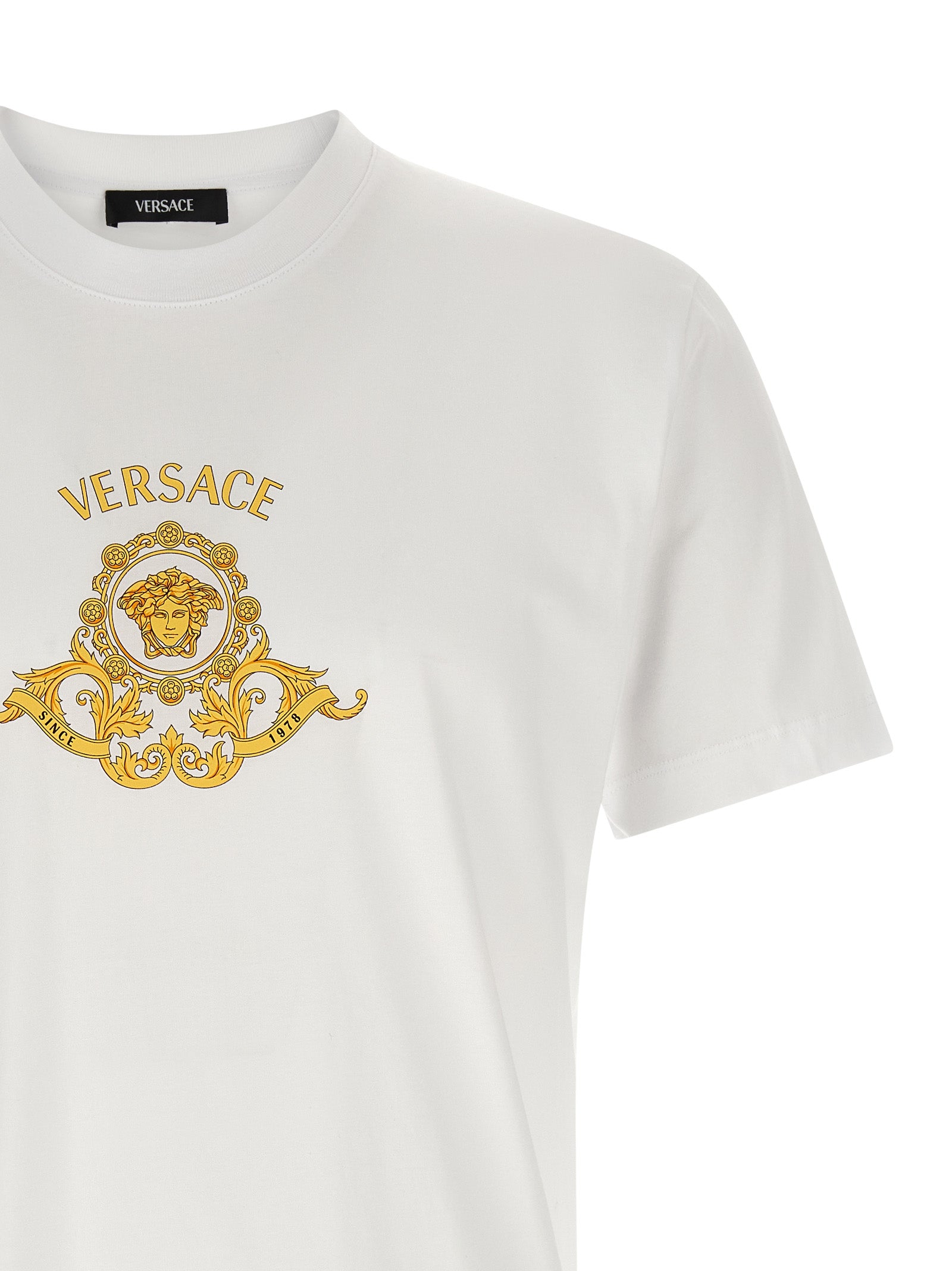Elevate your style with the Versace Hall of Heroes Crest T-Shirt, crafted from luxurious cotton, embodying sophistication and timeless elegance for the discerning individual.