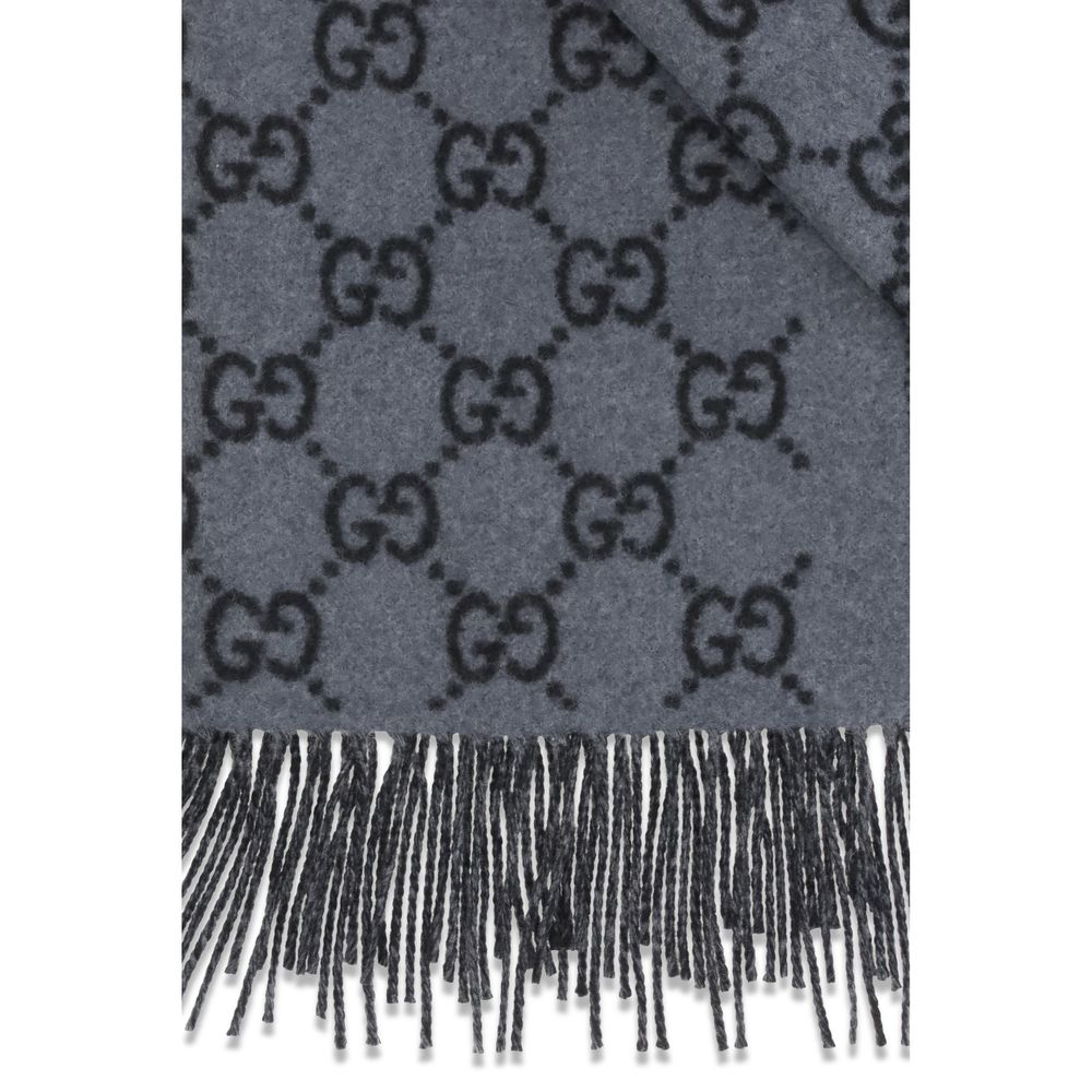 Indulge in the Gucci Blue Cashmere Foulard, a masterpiece of 100% cashmere, featuring an iconic GG pattern and delicate fringes, elevating your style with luxurious elegance.