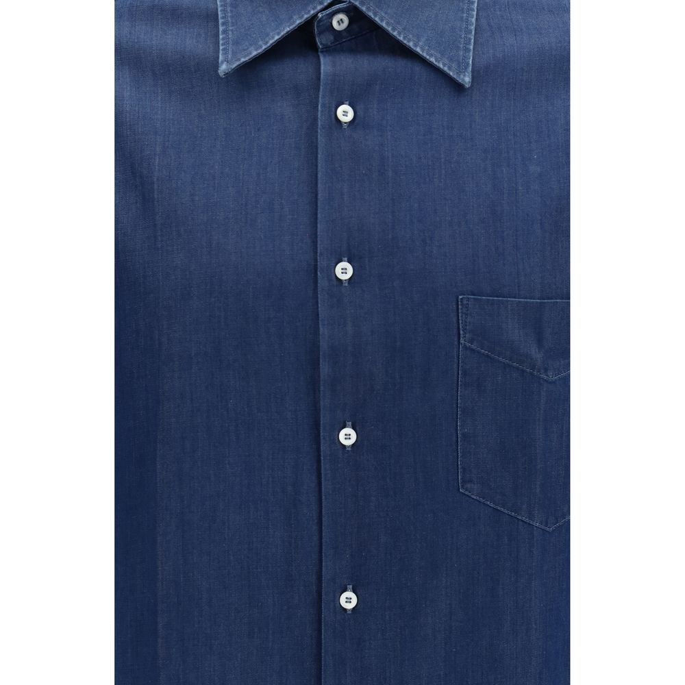 Experience the exquisite elegance of the Brunello Cucinelli Blue Denim Shirt, crafted from 100% cotton, embodying luxury and versatility for the discerning individual.