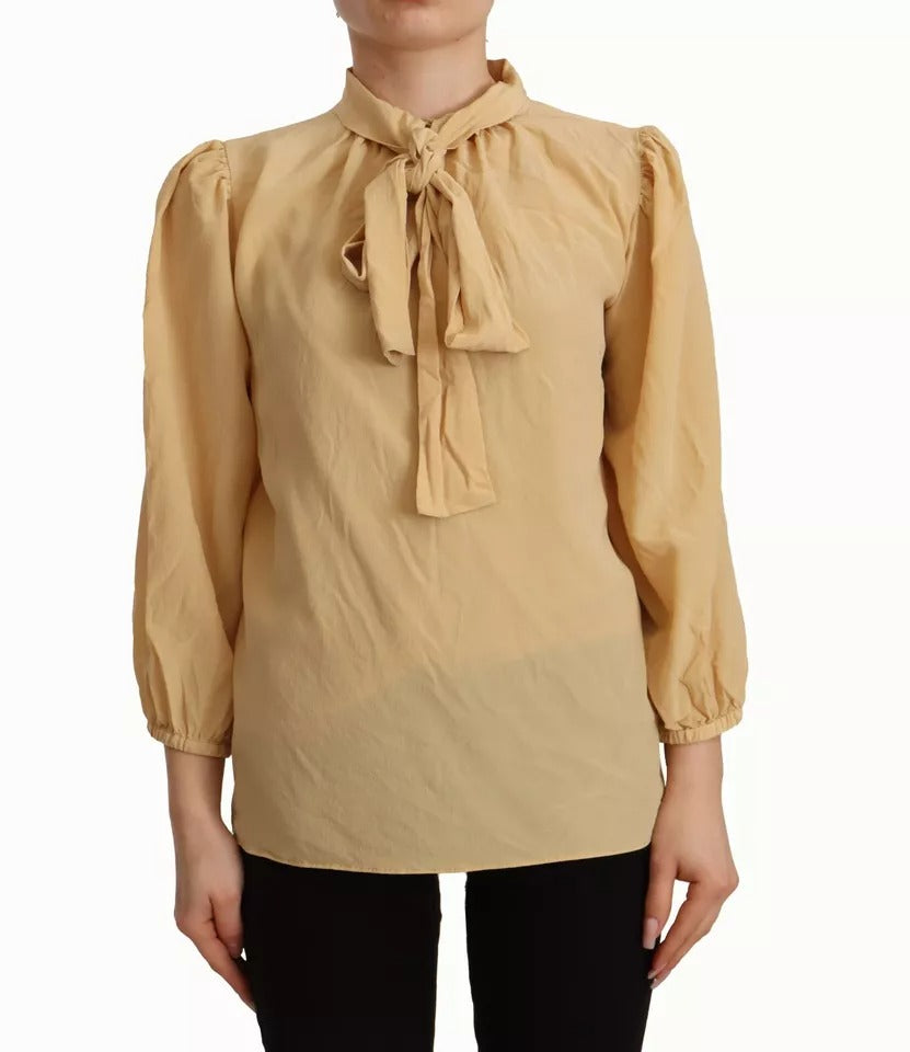 Indulge in the exquisite Dolce & Gabbana Mustard Ascot Collar Silk Blouse, a timeless piece of Italian craftsmanship that embodies luxury and sophistication for the discerning individual.