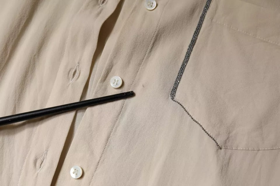 Indulge in the exquisite Brunello Cucinelli Beige Silk Blend Collared Button Down Top, a timeless masterpiece of luxury and elegance, crafted for those who appreciate true artistry.