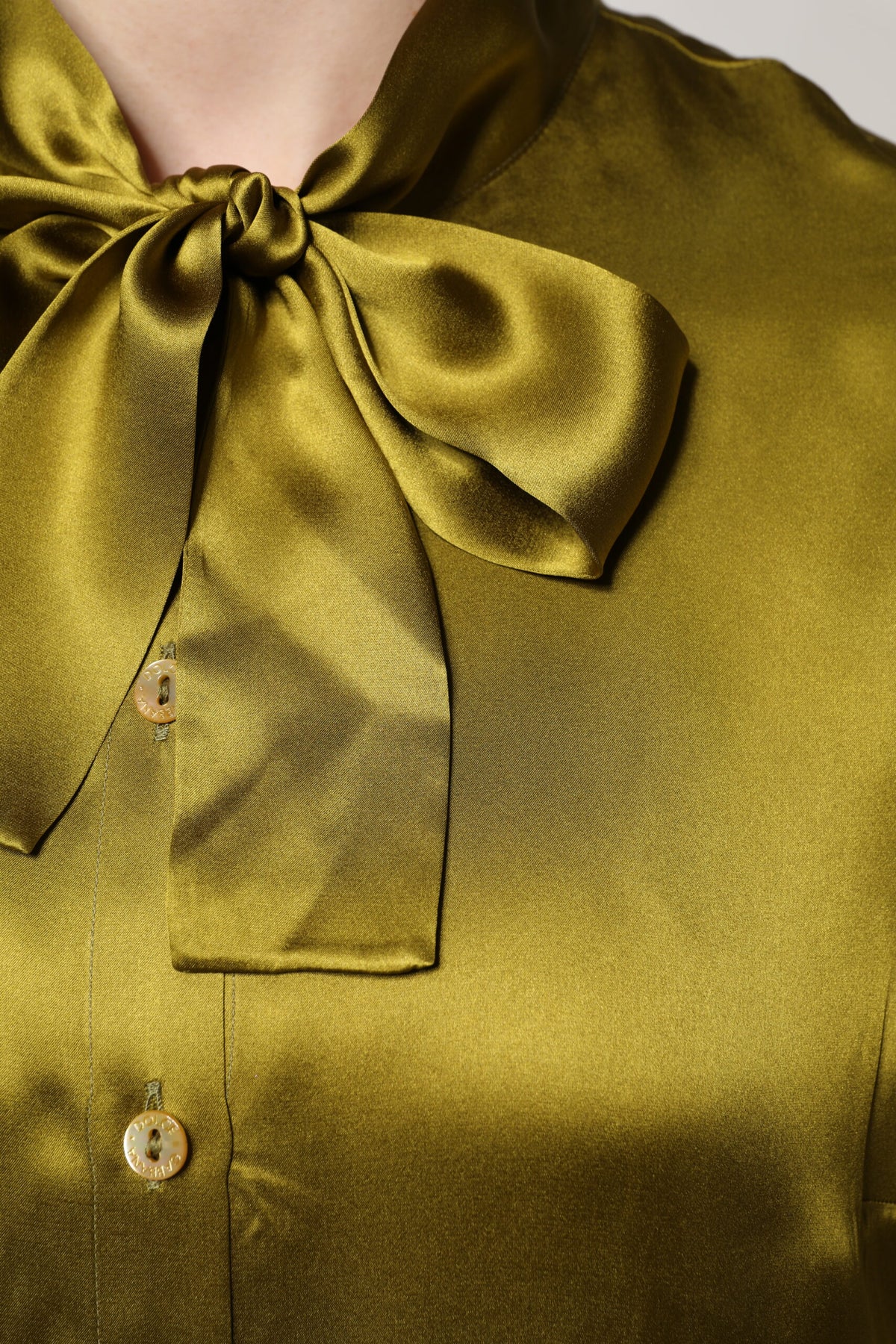 Experience the allure of Dolce & Gabbana's Olive Green Silk Ascot Collar Blouse, a testament to exquisite craftsmanship and timeless elegance, perfect for the discerning individual.