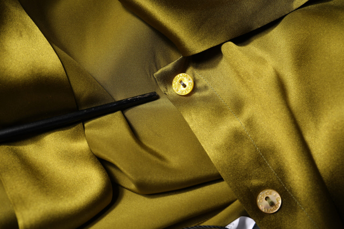 Indulge in the exquisite allure of Dolce & Gabbana's olive green silk ascot collar blouse, a timeless piece that embodies luxury and sophistication for the discerning individual.