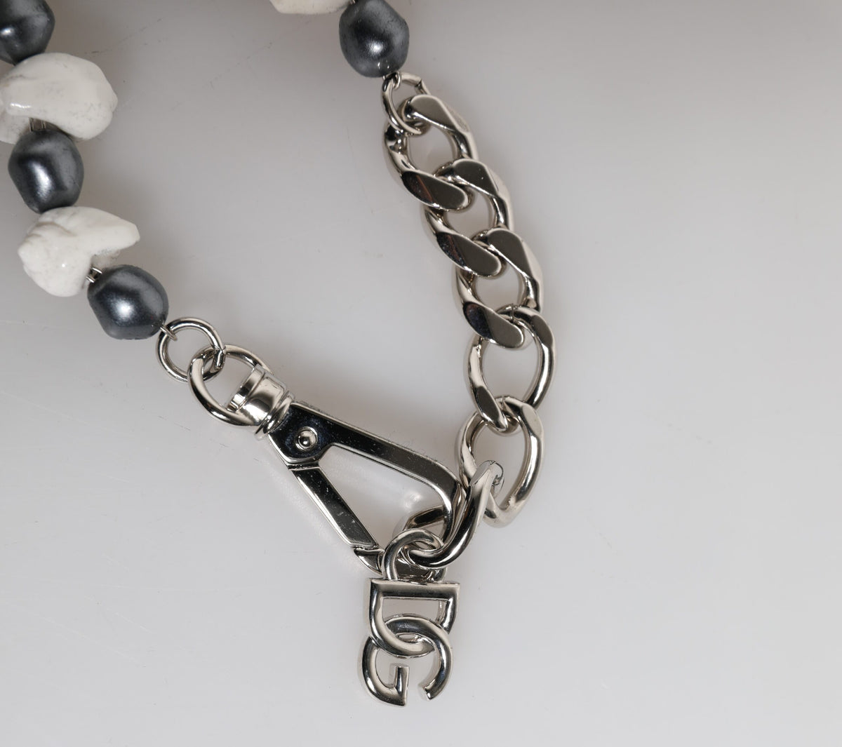 Elevate your elegance with the Dolce & Gabbana Silver Tone Brass Beaded Shell DG Logo Pendant Bracelet, a masterpiece of Italian craftsmanship blending luxurious pearls and bold design.