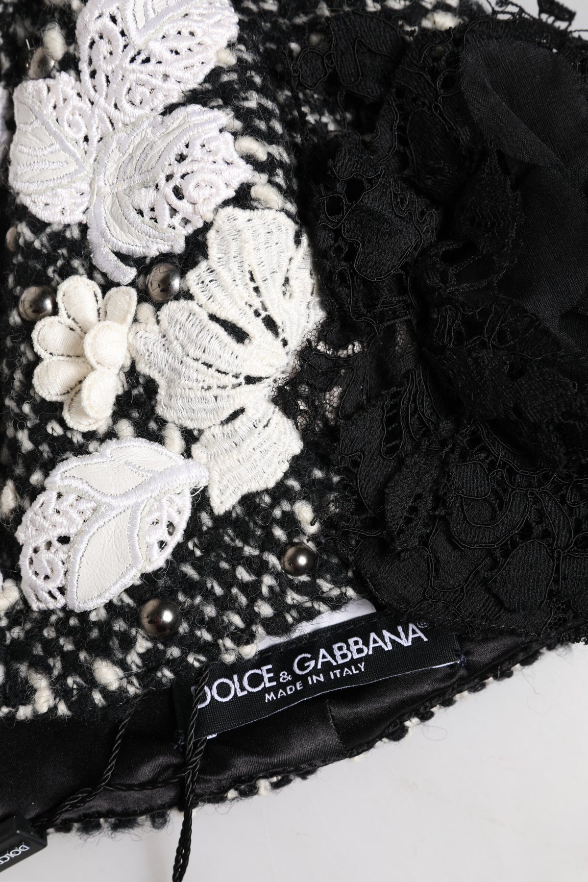 Discover the Dolce & Gabbana Black Wool White Floral Embellished Cloche Hat, a masterpiece of artisan craftsmanship that elevates your style with timeless elegance and luxurious allure.
