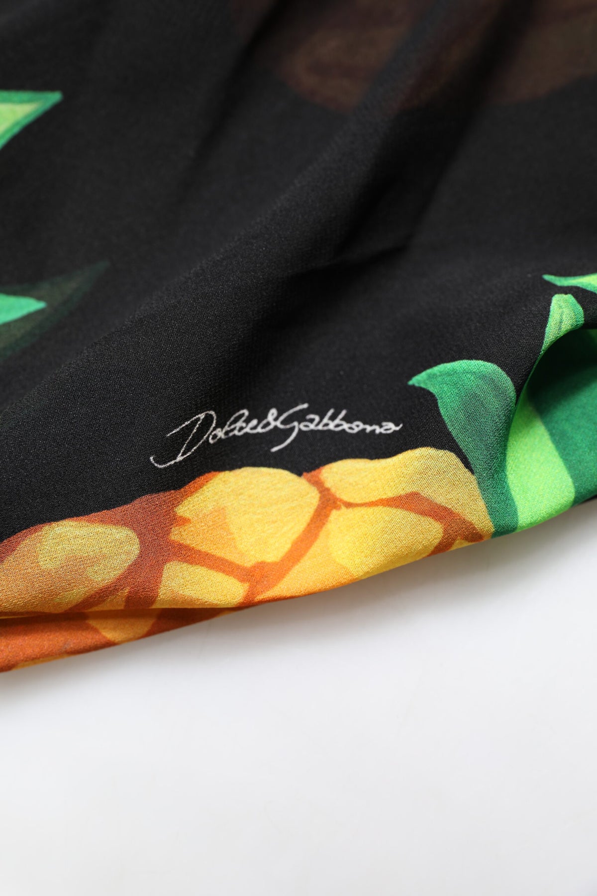 Indulge in the exquisite allure of the Dolce & Gabbana Black Pineapple Print Silk Wrap Mini Dress, a luxurious statement of Italian craftsmanship and timeless elegance.