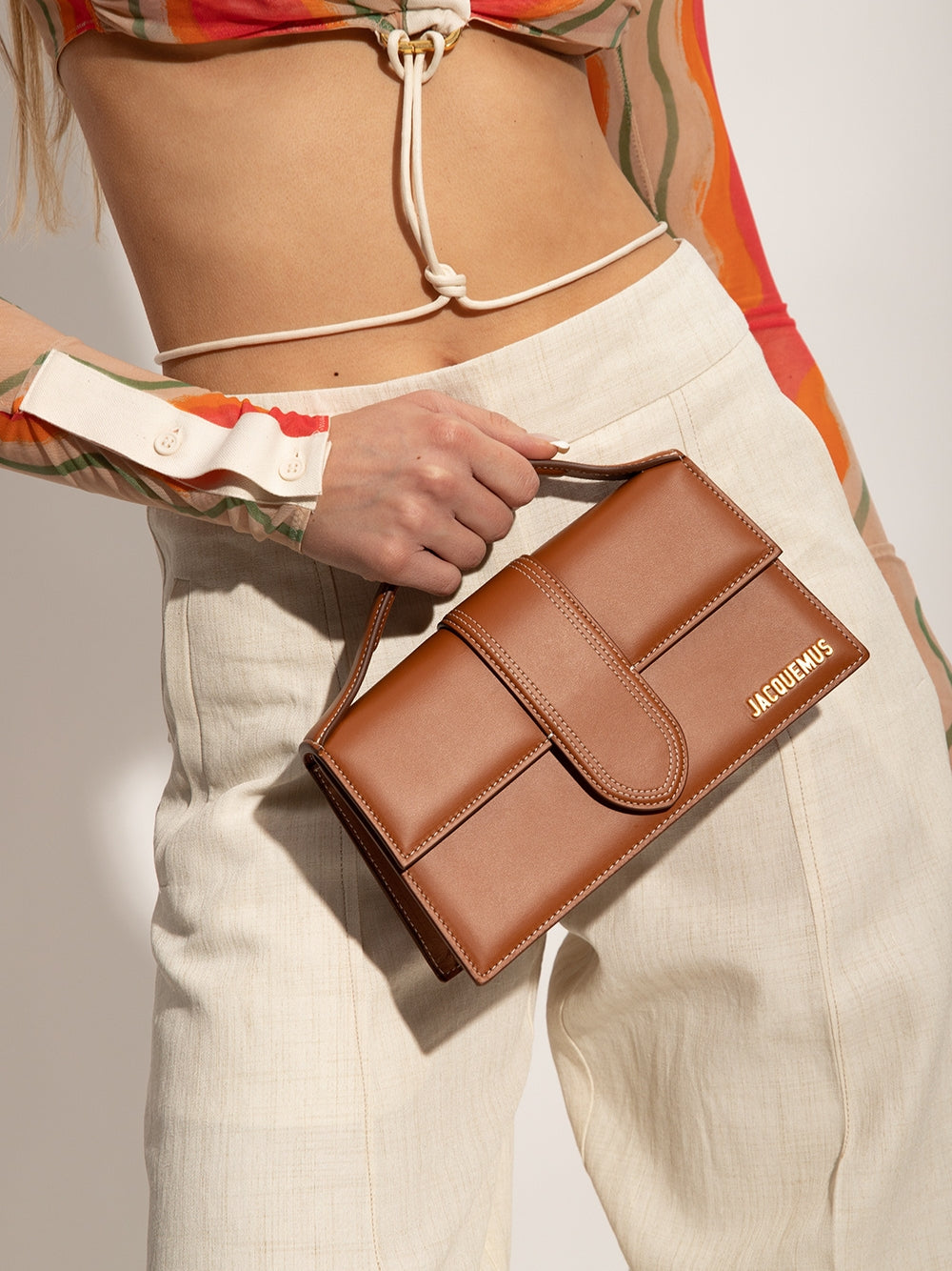 Indulge in the exquisite Jacquemus Le Grand Bambino light brown bag, a masterpiece of leather craftsmanship that embodies luxury and sophistication for the discerning individual.