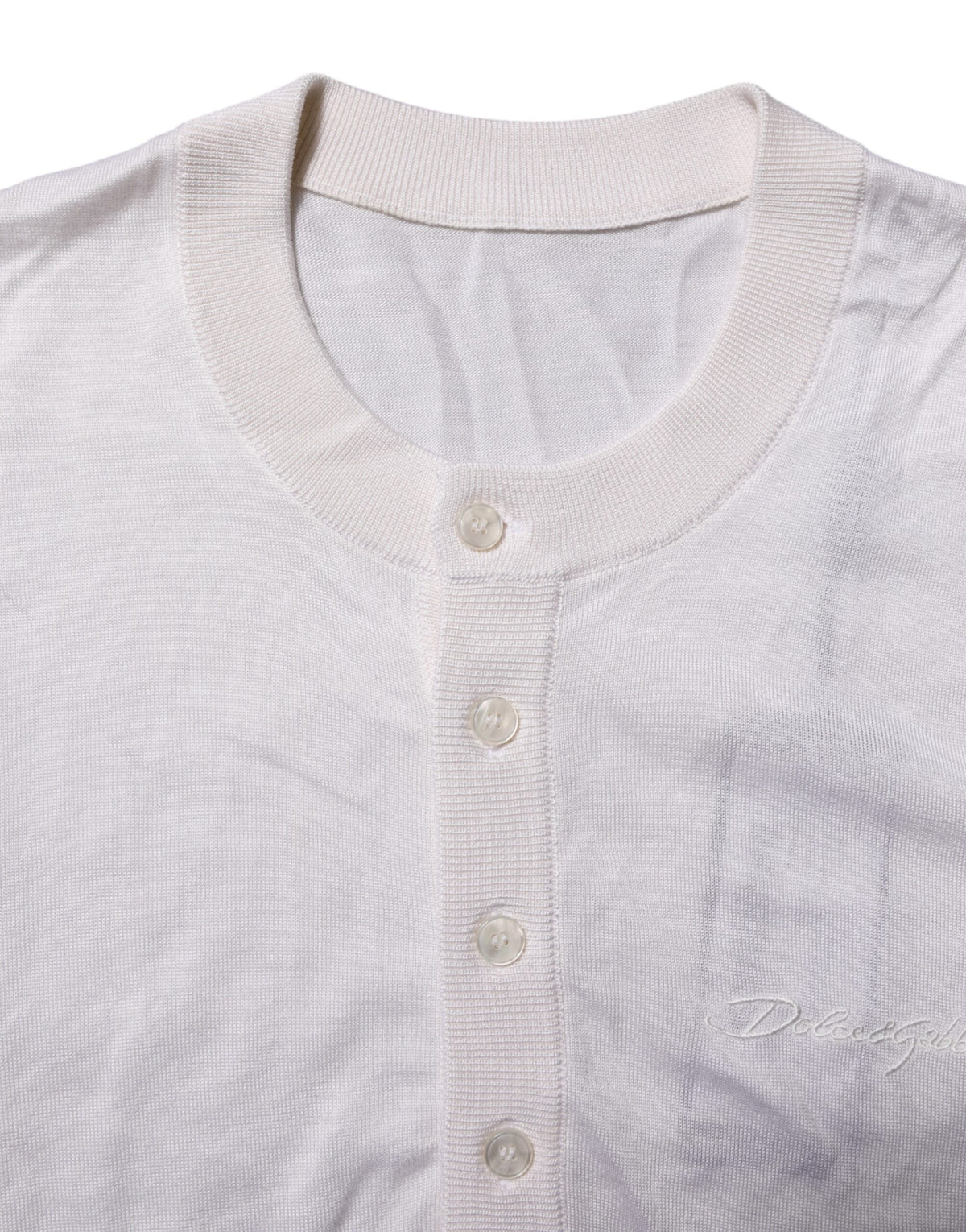 Indulge in the exquisite Dolce & Gabbana White Silk Henley T-shirt, where Italian craftsmanship meets timeless elegance, perfect for the discerning individual.