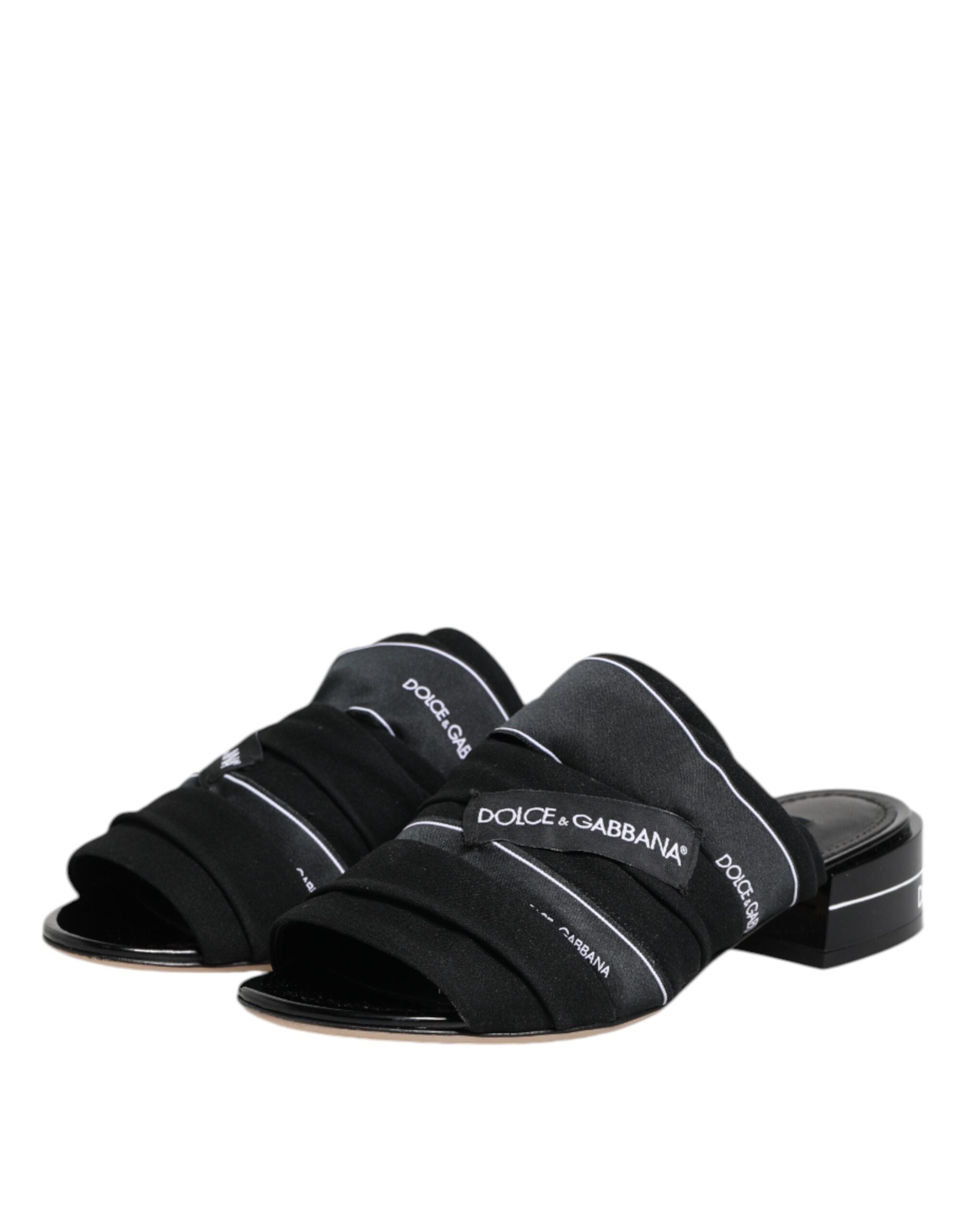 Indulge in the timeless elegance of Dolce & Gabbana Black Slides, crafted from premium fabric and leather, embodying luxury and sophistication for the discerning individual.