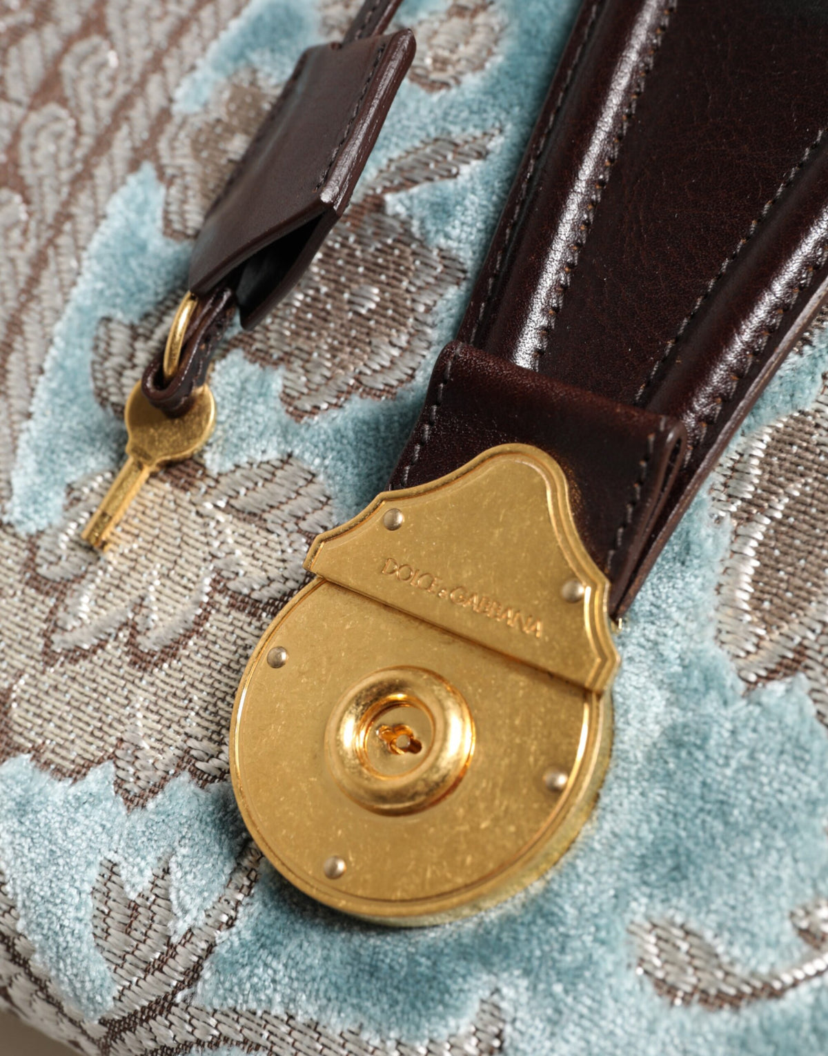 Discover the Dolce & Gabbana Blue Brown Leather Floral Jacquard Travel Handbag, a masterpiece of Italian craftsmanship blending premium leather and velvet for timeless elegance.