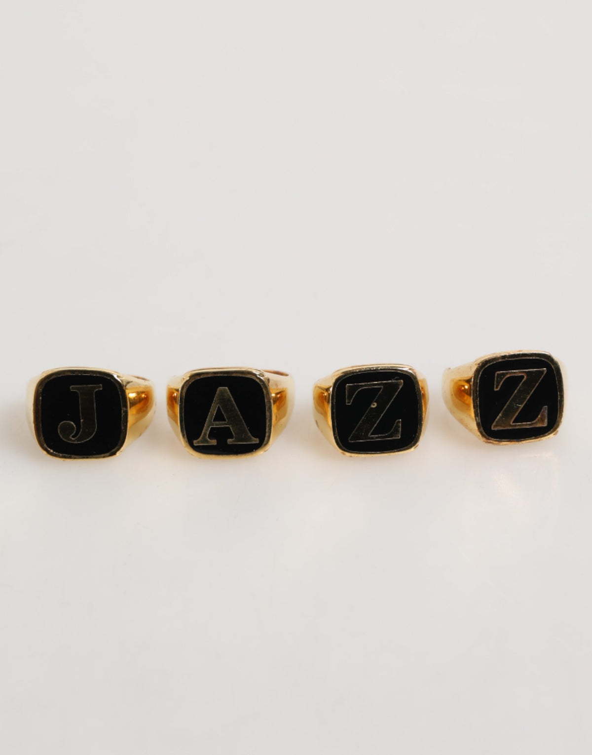 Discover the exquisite Dolce & Gabbana Gold Tone Brass JAZZ Letter Set, a luxurious blend of silver and enamel, embodying artistry and sophistication for the discerning individual.