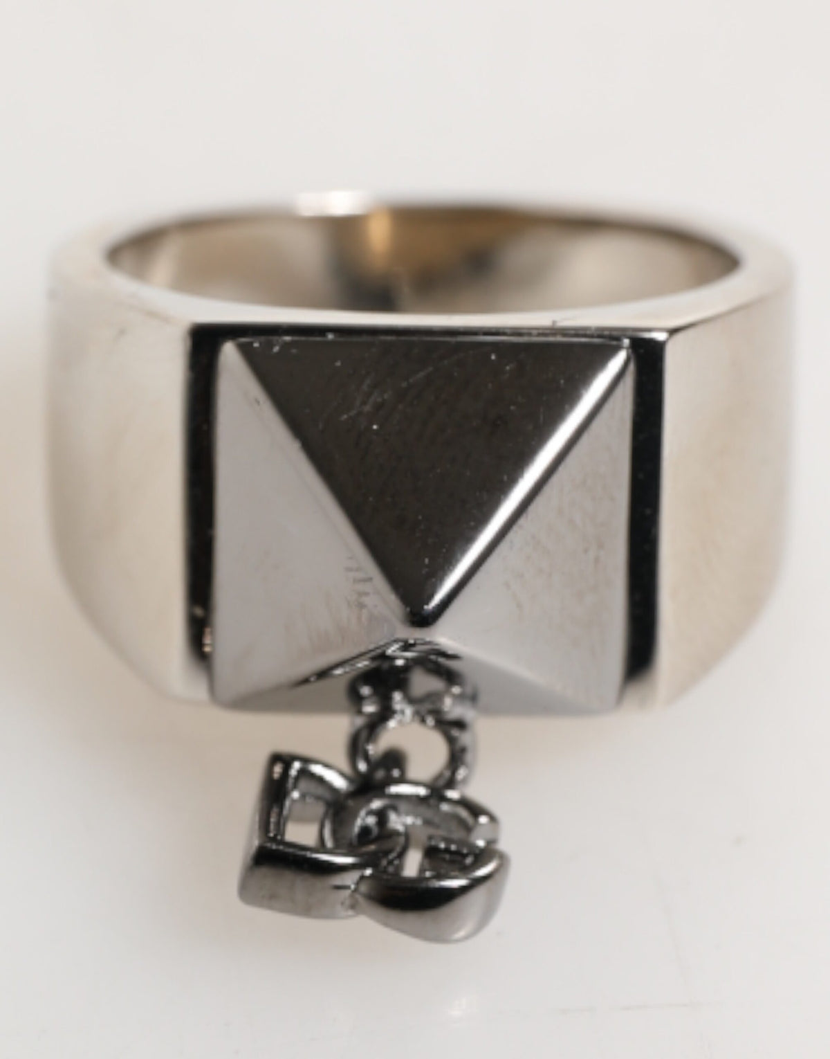 Indulge in the exquisite allure of the Dolce & Gabbana Silver Tone Pyramid DG Logo Ring, a statement piece of Italian craftsmanship that embodies modern luxury and sophistication.