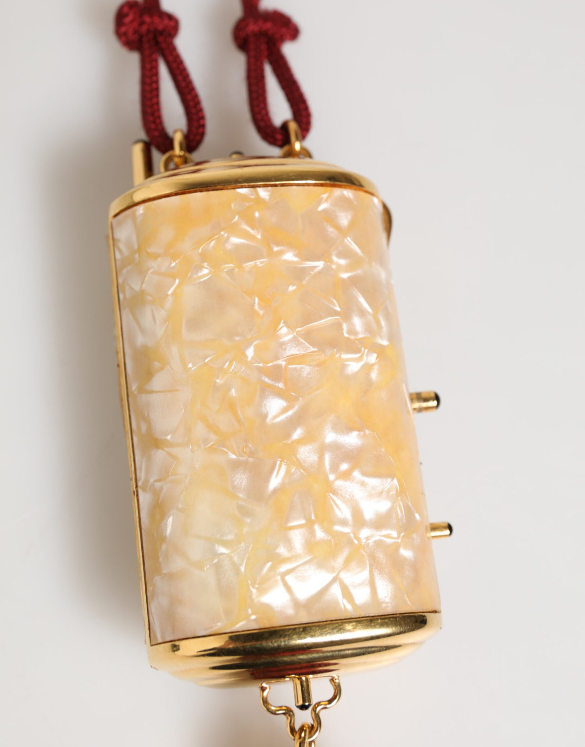 Indulge in the allure of the Dolce & Gabbana White Pearl Resin Gold Metal Red Tassel Pendant Bag, a masterpiece of exquisite craftsmanship and timeless luxury.