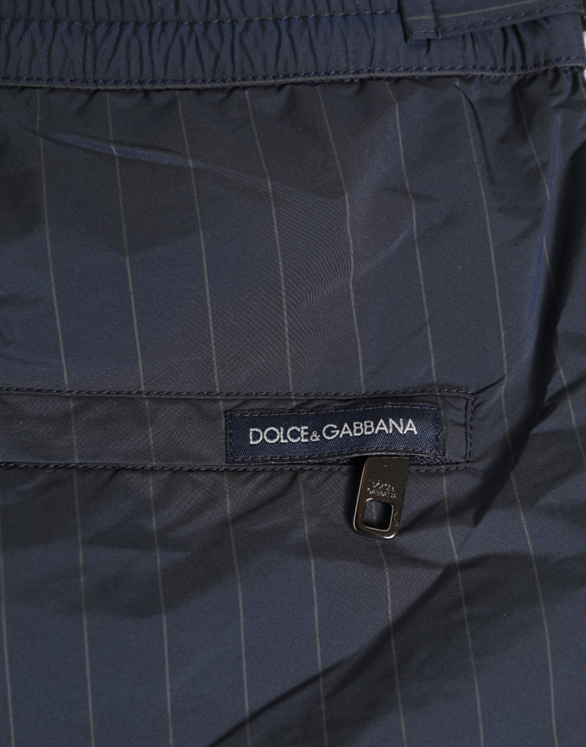 Experience the refined elegance of Dolce & Gabbana's navy blue pinstripe swim shorts, crafted from premium materials for effortless sophistication and timeless allure.