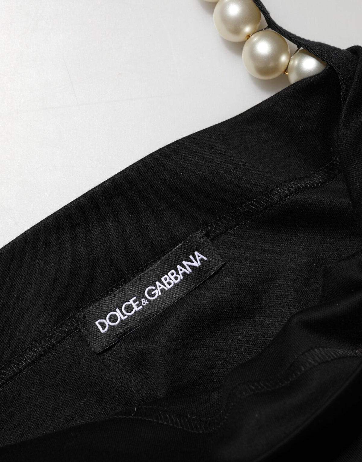 Experience the allure of the Dolce & Gabbana Black Faux Pearl Cotton Sheath Mini Dress, a masterpiece of Italian craftsmanship that embodies timeless elegance and sophisticated luxury for every occasion.