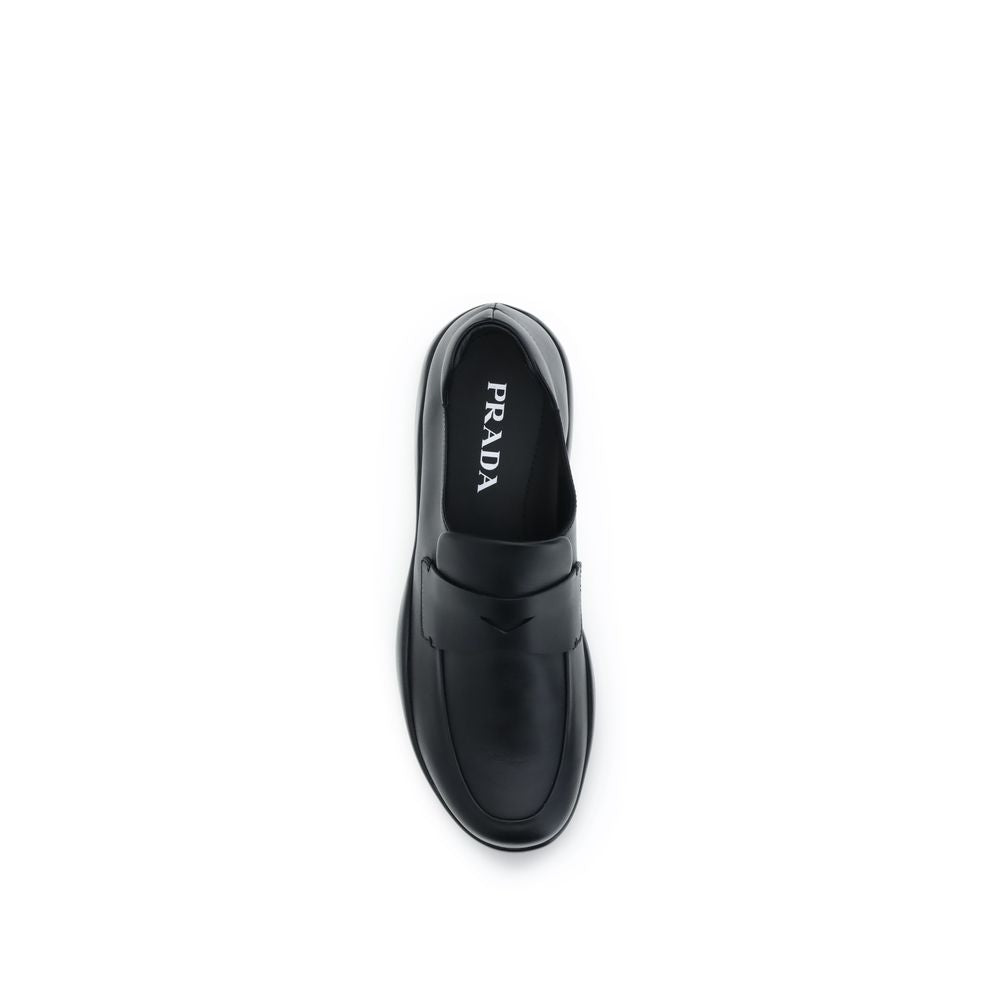Indulge in the exquisite craftsmanship of Prada's Black Calf Leather Bos Taurus Slip-On Loafers, where timeless elegance meets contemporary design for the discerning individual.