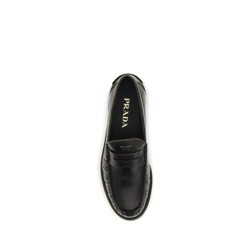 Elevate your style with Prada's Black Calf Leather Bos Taurus Slip-On Loafers, where exquisite craftsmanship meets timeless elegance for the discerning individual.
