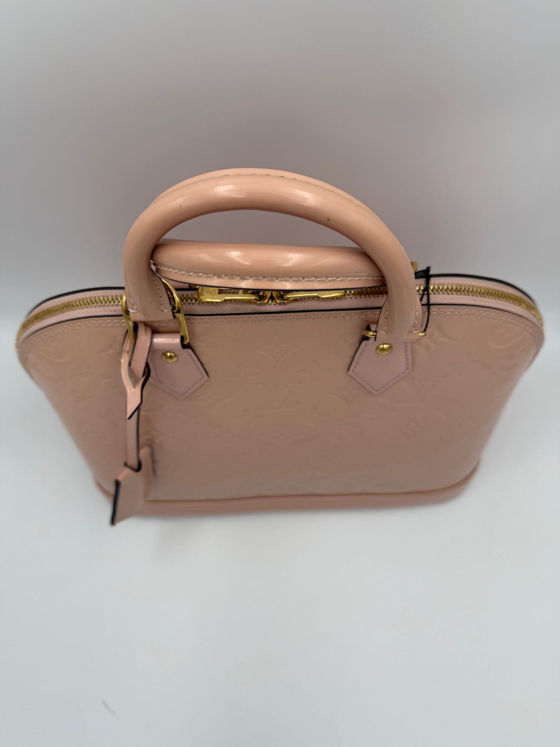 Elevate your style with the Louis Vuitton Alma MM Pink Patent Monogram Handbag, a timeless piece that embodies exquisite craftsmanship and iconic luxury.