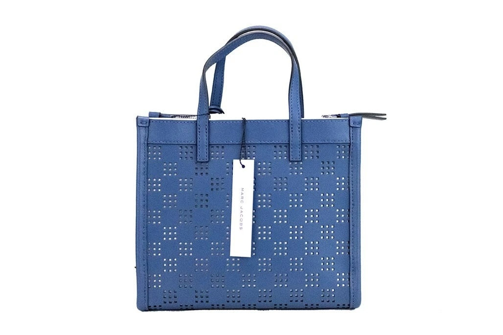 Elevate your style with the Marc Jacobs Mini Grind Blue Sea Perforated Leather Crossbody Tote, a testament to exquisite craftsmanship and timeless elegance.
