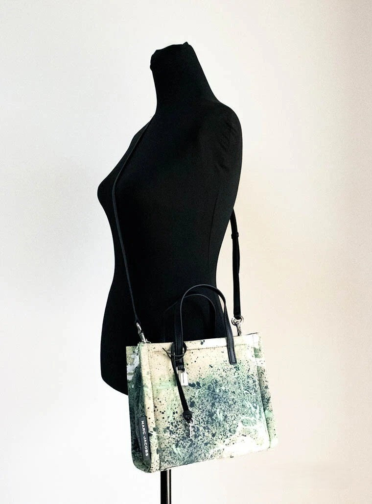 Elevate your style with the Marc Jacobs Mini Green Multi Splatter Paint Print Nylon Crossbody Tote, a masterpiece of vibrant artistry and exquisite craftsmanship, perfect for any occasion.