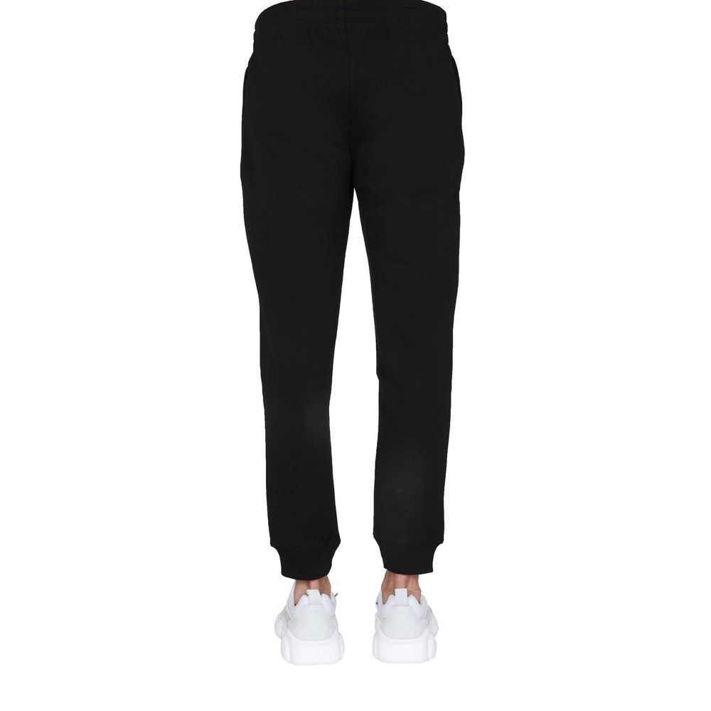 Elevate your wardrobe with Moschino Couture Black Cotton Joggers, crafted from luxurious cotton for a tapered fit that embodies sophistication and effortless style.