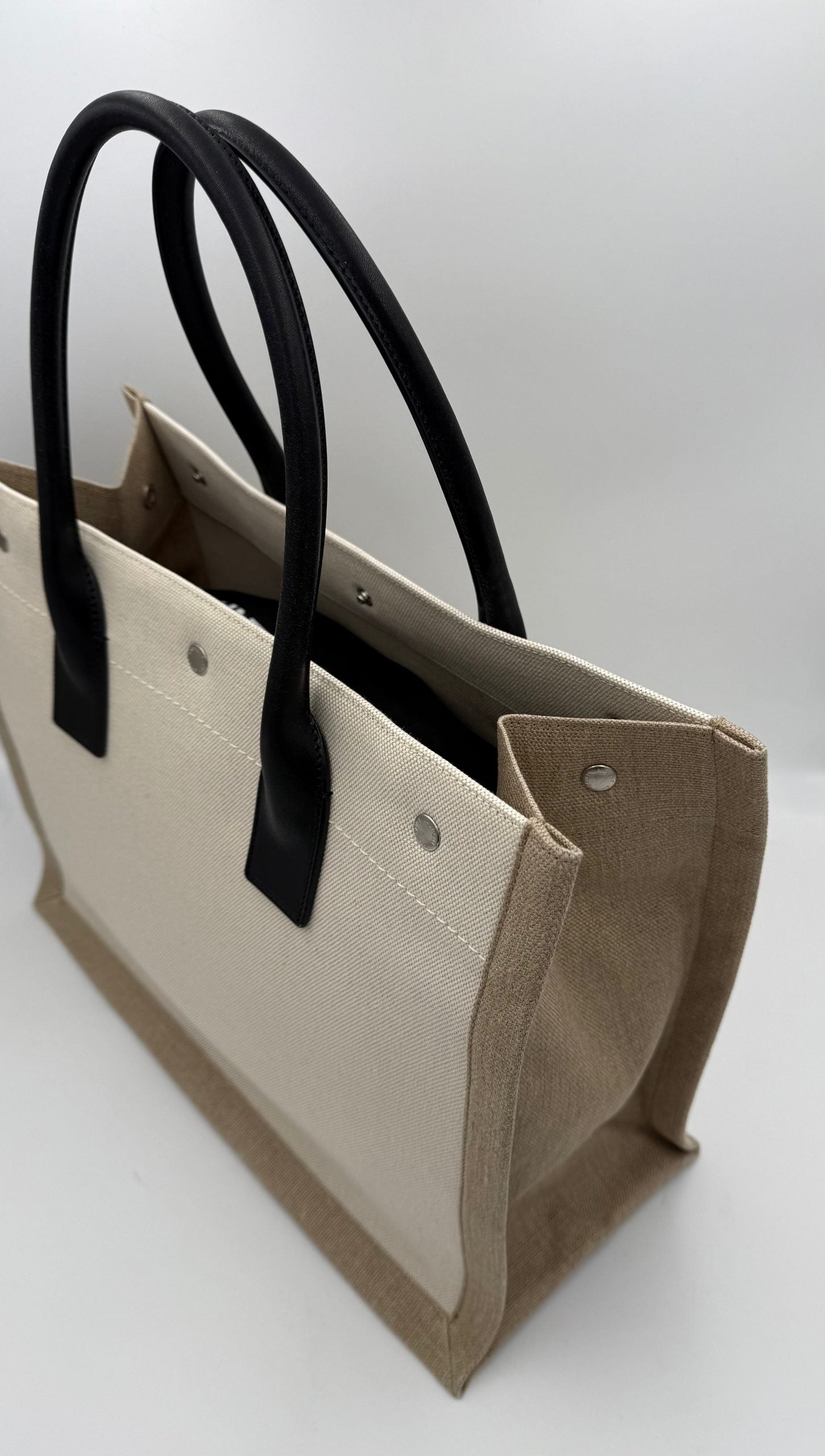 Discover the Saint Laurent Rive Gauche Medium Tote Bag, a blend of scratch-resistant leather and fabric, embodying timeless elegance and sophisticated versatility for the discerning individual.