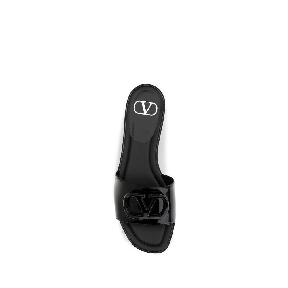 Indulge in the elegance of Valentino Garavani's Black Calf Leather Bos Taurus Flat Sandals, where glossy patent leather meets sophisticated design for timeless luxury.