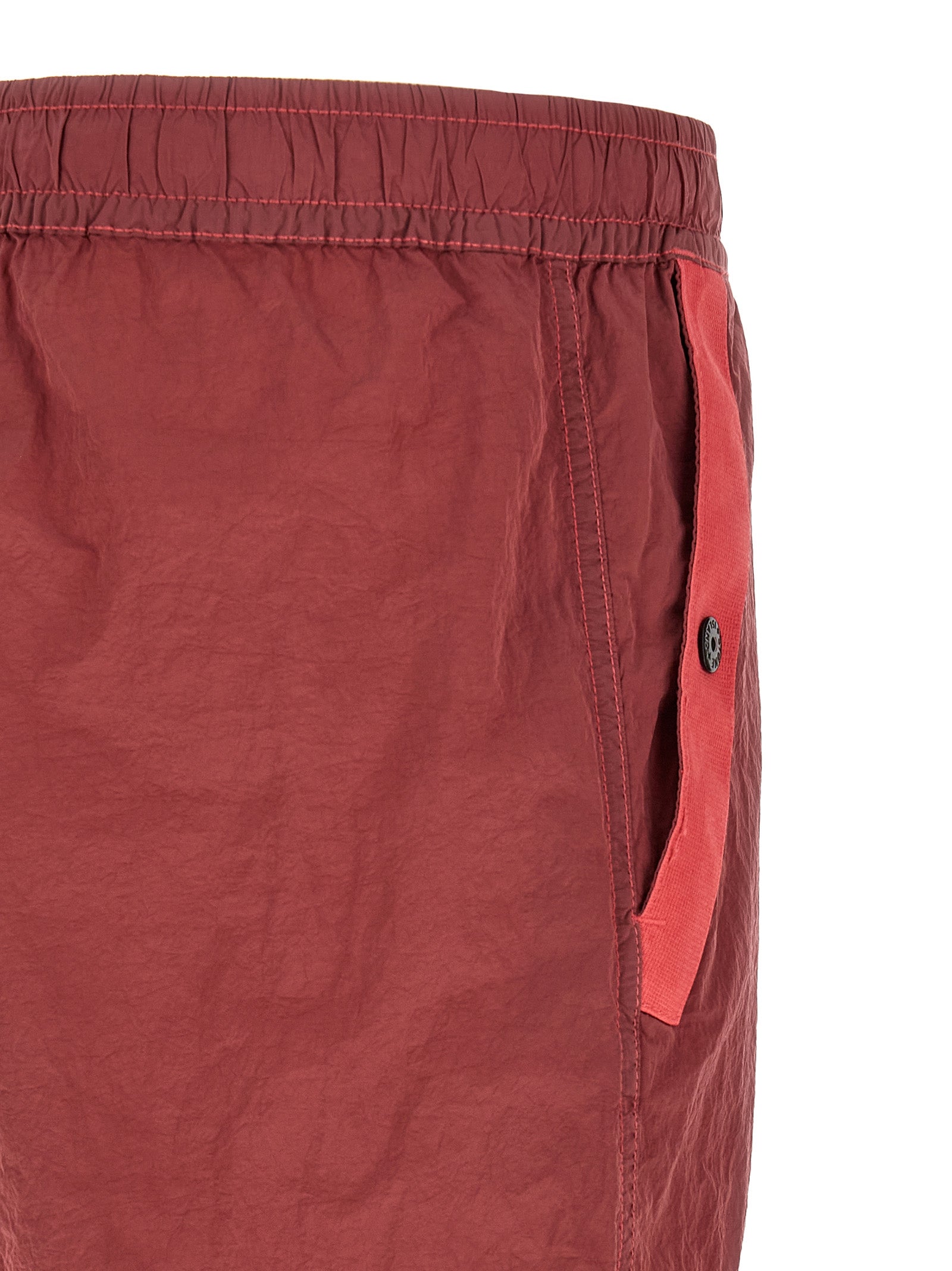 Elevate your urban wardrobe with Stone Island's Red Polyamide Joggers, crafted from innovative Nylon Metal Econyl® for a sophisticated, iridescent finish that embodies luxury and style.