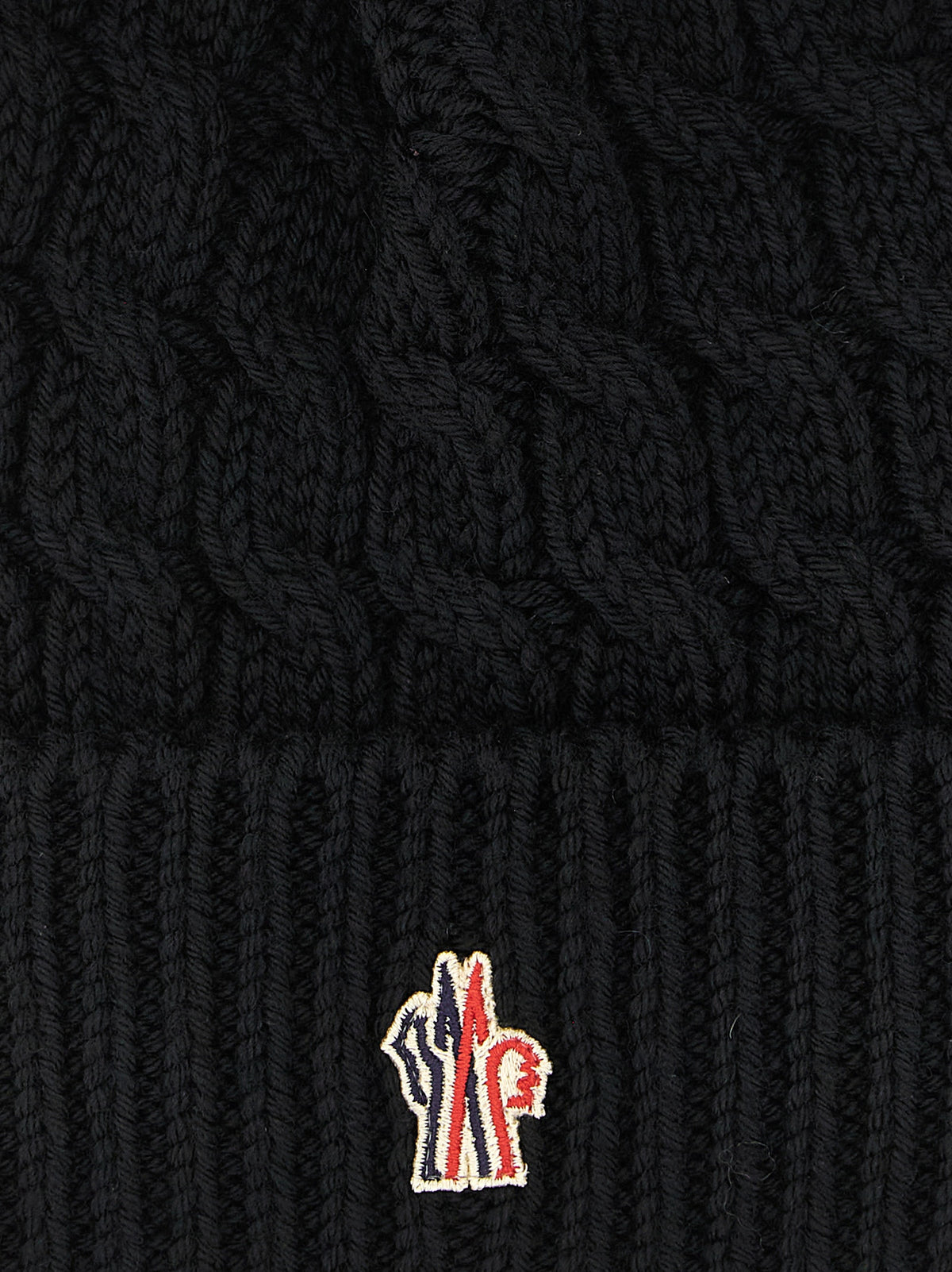 Indulge in the exquisite Moncler Grenoble Black Virgin Wool Beanie, a symbol of alpine elegance crafted from 100% virgin wool, perfect for mastering winter sophistication.